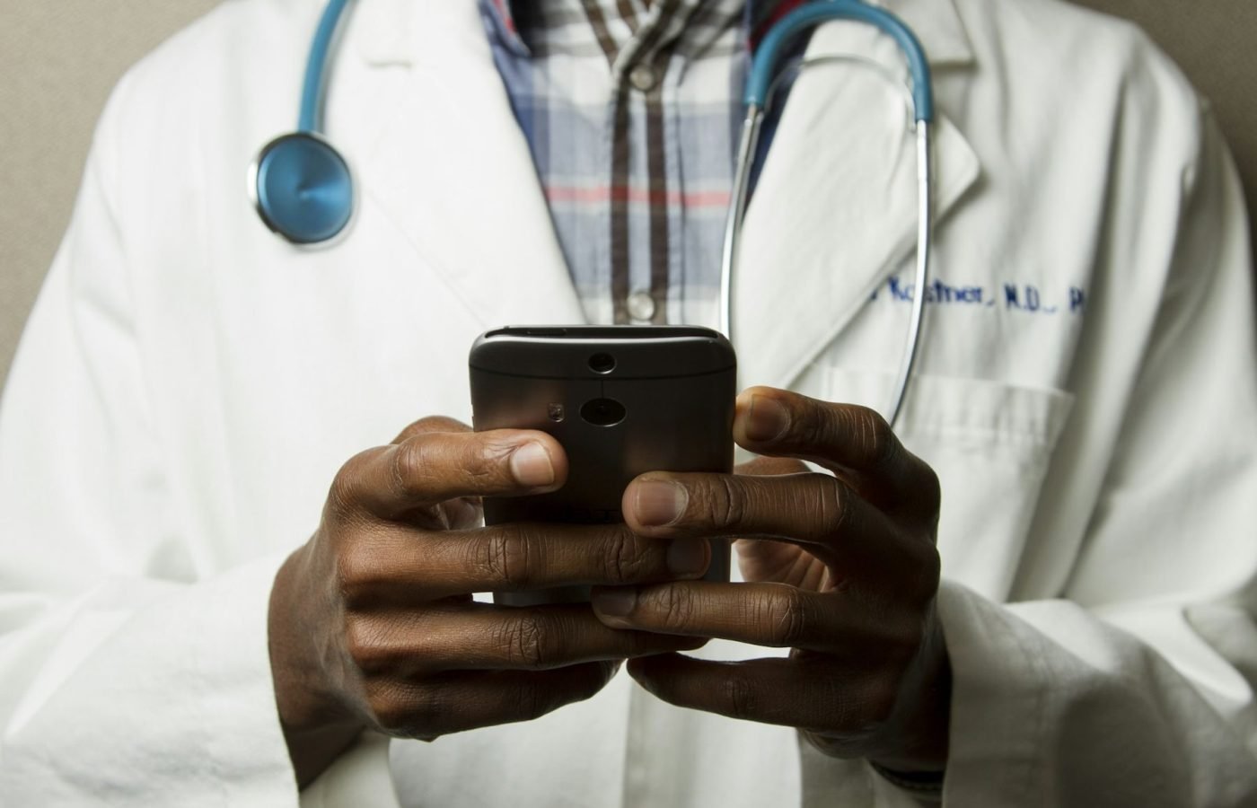 Clinician in a white coat checking a smartphone