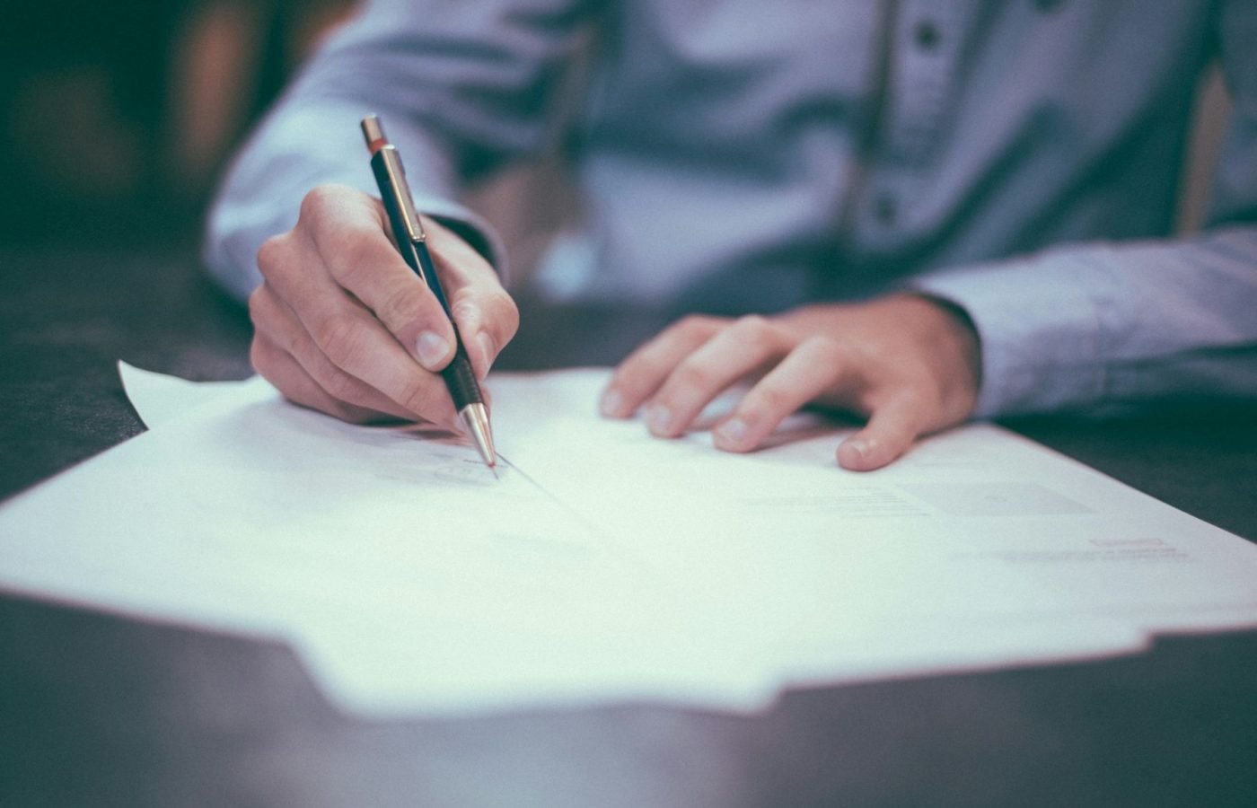 Person signing a printed document with a pen