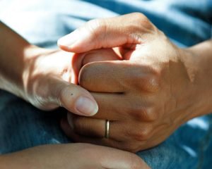Two people holding hands in a gesture of support