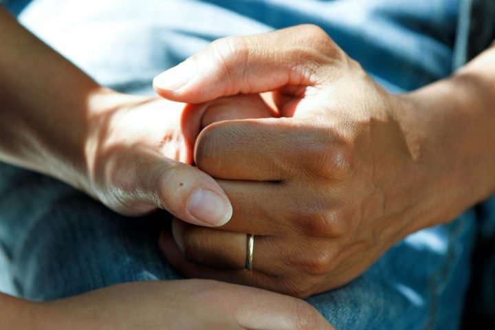 Two people holding hands in a gesture of support
